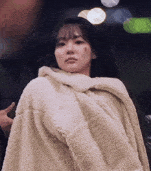 a woman is wrapped in a fluffy blanket and has a bruise on her face