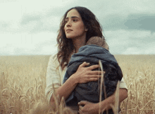a woman is holding a child in a field of wheat