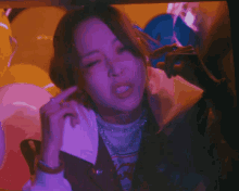 a woman with her eyes closed is wearing a jacket and a necklace with the letter s on it