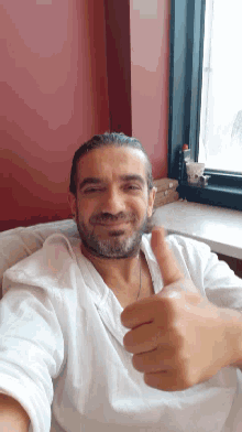 a man in a white shirt is giving a thumbs up sign