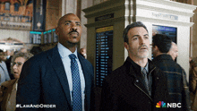 two men are standing next to each other in front of a sign that says departures