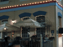 a man sits outside a restaurant with umbrellas and a sign that says no smoking