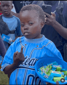 a young boy wearing a tear jersey holds a basket of candy