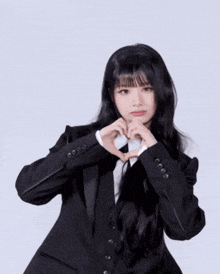 a woman in a suit making a heart shape with her hands