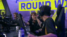 a group of people are sitting in front of a sign that says round