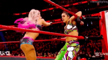 two women are wrestling in a ring while a referee looks on .