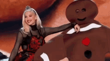 a woman is standing next to a large gingerbread man .