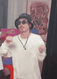 a man wearing a hat , sunglasses , and a necklace is dancing in a room .