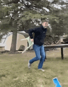 a man in a black nike sweatshirt is running in a field