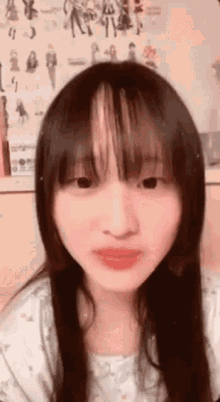 a close up of a woman 's face with a poster on the wall in the background