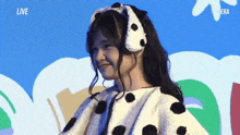 a woman wearing a dalmatian costume is smiling in front of a blue background that says live