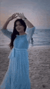 a woman in a blue dress is dancing on the beach with the words ben gunesim ben yakarim below her