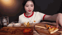 a woman is sitting at a table eating pizza and pickles