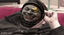 a person laying on a bed with a helmet on their head that looks like a vampire with blood coming out of his mouth