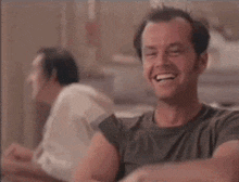 a man in a green shirt is smiling while another man looks on