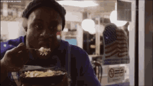 a man is eating a bowl of food in front of a sign that says no smoking