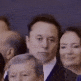 a man in a suit is standing in a crowd of people and looking at the camera .