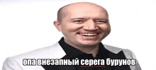 a bald man wearing a white jacket and black shirt is smiling in a foreign language .