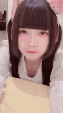 a girl with long black hair and a white shirt is laying on a bed