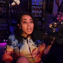 a woman wearing headphones and a tie dye shirt is speaking into a microphone