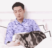a man is laying in bed with a cat on top of him .