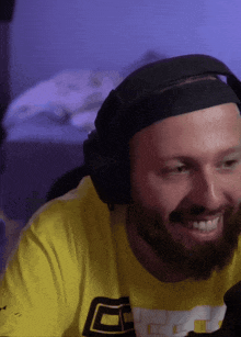 a man with a beard wearing headphones and a yellow shirt with the letter g on it