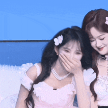a girl covering her mouth with her hand while another girl laughs