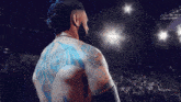 a man with blue tattoos on his back stands in front of a crowd