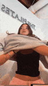 a woman is taking off her shirt in front of a sign that says " 23tajjjht "