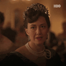 a woman wearing a pearl necklace and a tiara with hbo on the bottom right