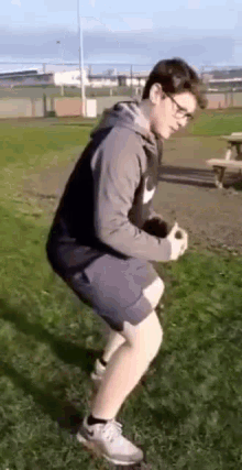 a young man is doing squats in a park with a ball .