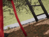 a red and black ladder is sitting in the dirt in a park