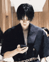 a man in a black jacket looks at his phone