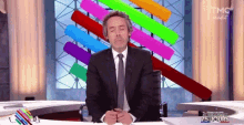 a man in a suit and tie is sitting at a desk with his eyes closed in front of a sign that says 75 jours
