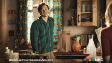 a man in a plaid shirt stands in a kitchen next to a woman and a bottle of milk