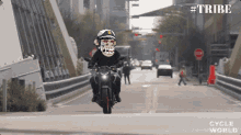 a man riding a motorcycle with a monkey on his face and the words #tribe on the bottom