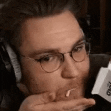 a man wearing glasses and headphones is eating a piece of cheese .