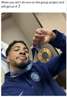 a man in a blue jacket is holding up a gold medal