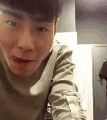 a young man is making a funny face while looking at the camera in a room .