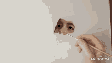 a hand is holding a brush in front of a hole in a piece of paper that says made in animonica