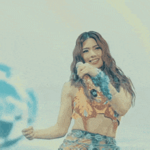 a woman singing into a microphone while wearing a crop top and skirt