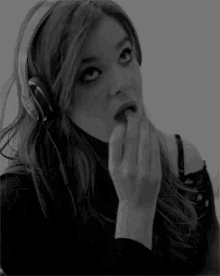 a black and white photo of a woman wearing headphones and making a funny face .