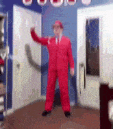a man in a red suit is dancing in a room .