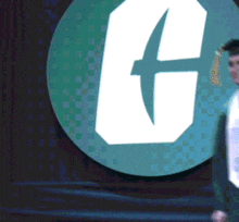 a man is standing in front of a green circle with a white letter g on it