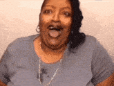 a woman in a grey shirt is making a funny face with her mouth open