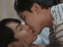 two men are kissing each other on the forehead .