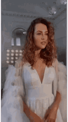 the woman is wearing a white dress with a plunging neckline and ruffled sleeves .