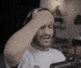 a man wearing headphones is holding his head in pain while sitting in front of a microphone .