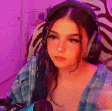 a woman wearing headphones is sitting in front of a microphone in a room .