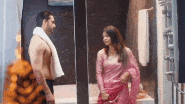 a shirtless man and a woman are standing in a bathroom .